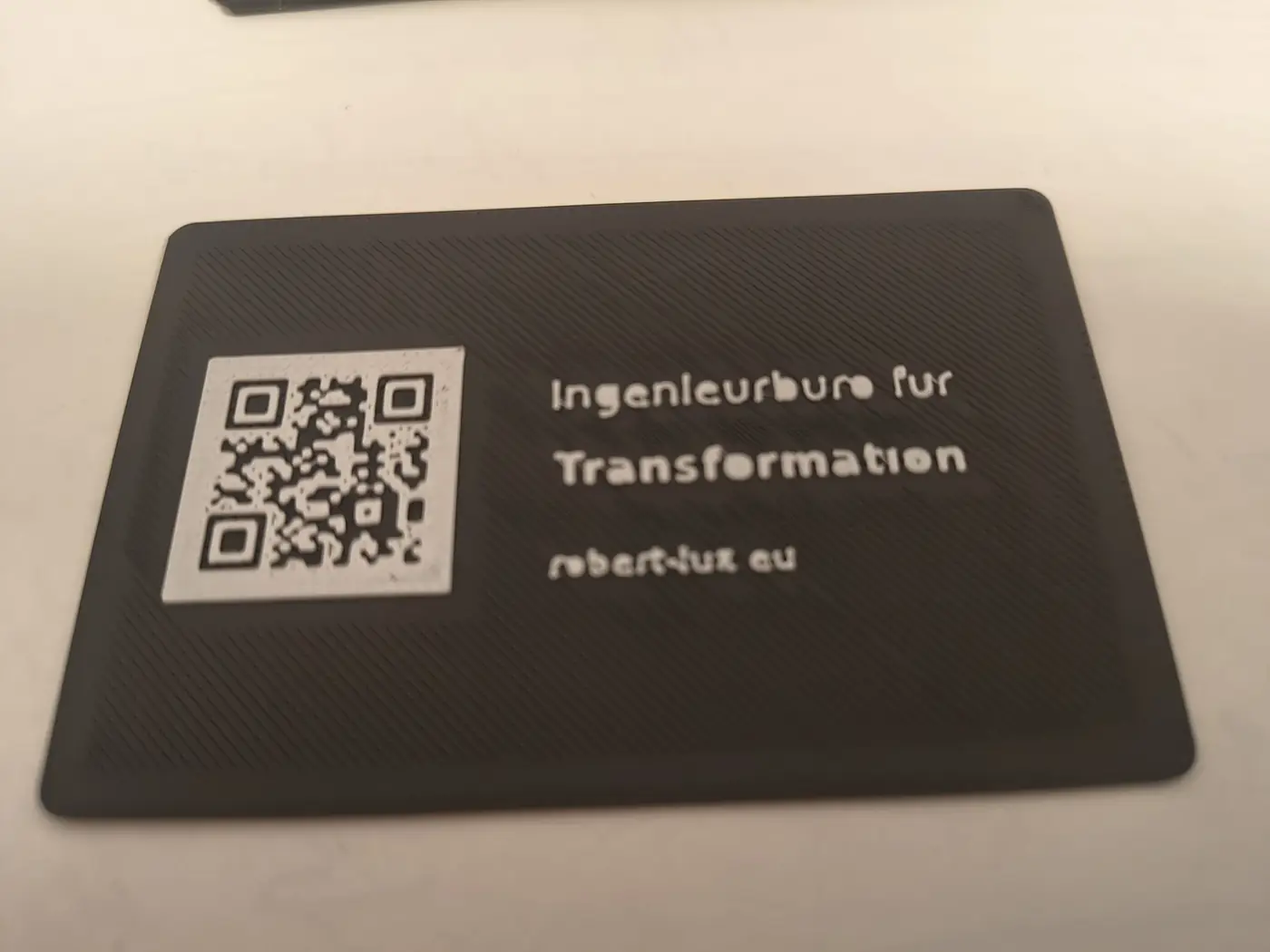 3D-gedruckte Visitenkarte im Querformat mit QR-Code und Schriftzug Ingenieurbüro für Transformation